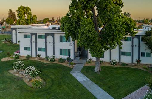 A white building with a tree in front of it.