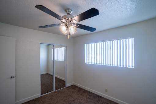 A room with a ceiling fan and a window with blinds.