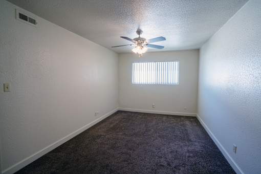 A room with a ceiling fan and carpeted floor.