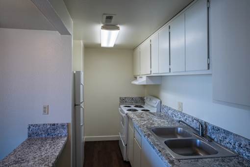 A kitchen with a sink, stove, and cabinets.