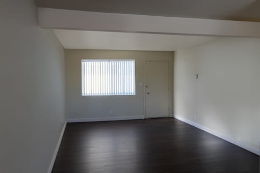 A room with a window and wooden floors.