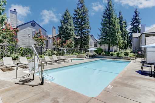 A swimming pool surrounded by lounge chairs and trees.