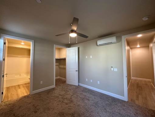 A room with a ceiling fan and a wall-mounted air conditioner.