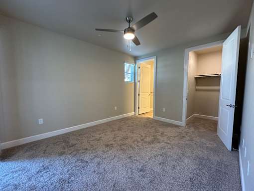 A room with a ceiling fan and carpeted floor.