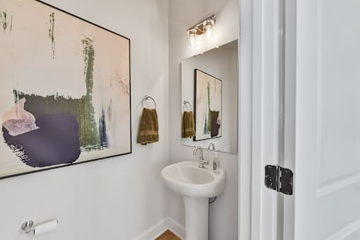 A bathroom with a white sink and a painting on the wall.