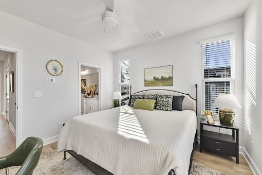 A bedroom with a large bed, a green chair, and a painting on the wall.
