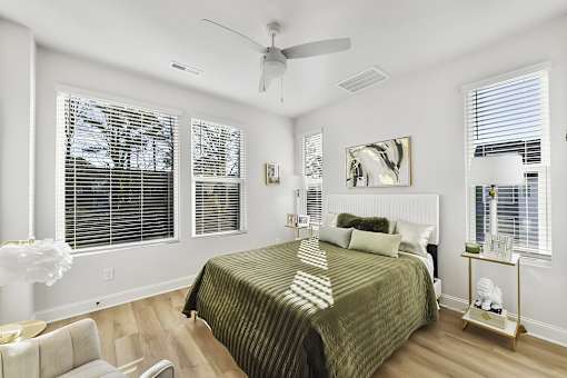 A bedroom with a bed, chair, and a ceiling fan.
