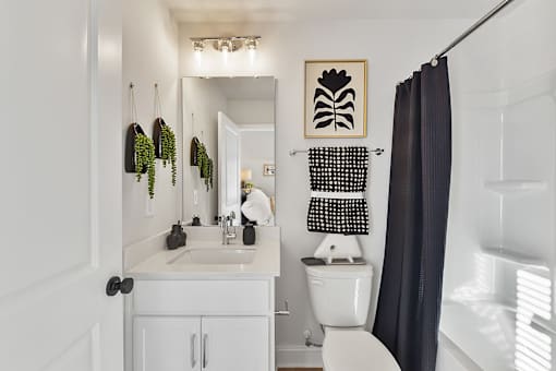 A white bathroom with a toilet, sink, and a mirror.