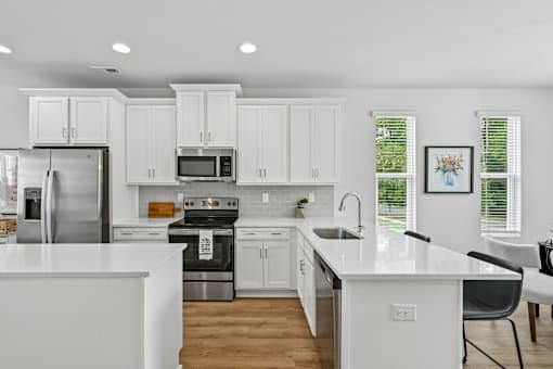 A modern kitchen with white cabinets and stainless steel appliances.