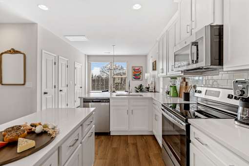 A kitchen with white cabinets and a wooden island.