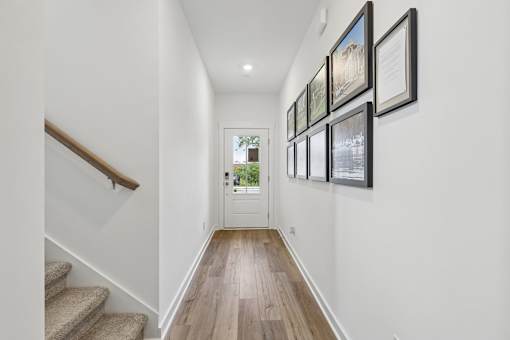A hallway with a staircase and pictures on the wall.