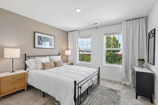 A bedroom with a large bed, two lamps, and a window with curtains.