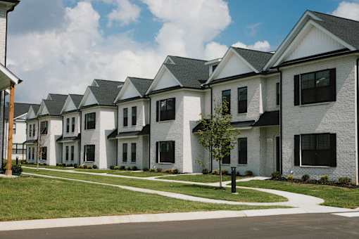 A row of white houses with black shutters and grey roofs.