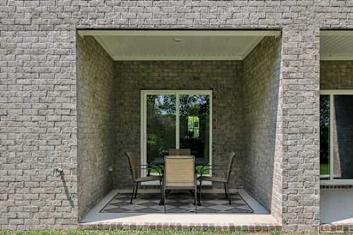 A patio with a table and chairs is framed by a brick wall.