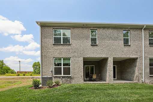 A grey brick house with a green lawn in front.