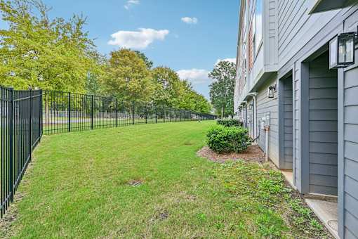 A black fence surrounds a green lawn in front of a building.