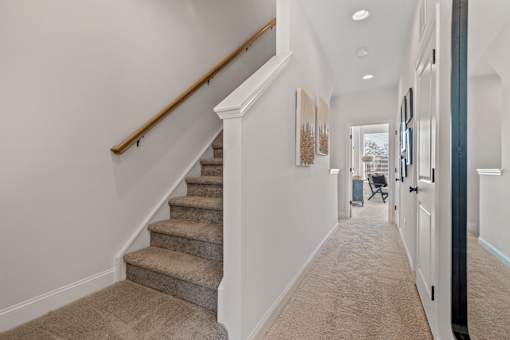 A hallway with a staircase and a wall with pictures.