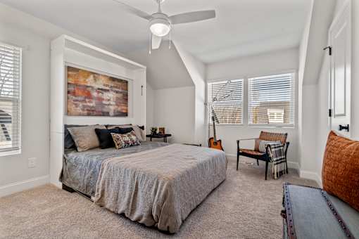 A bedroom with a large bed and a ceiling fan.