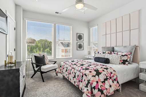 A bedroom with a bed, chair, and window.