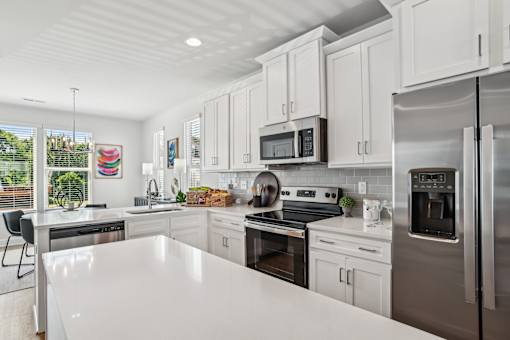 A modern kitchen with white cabinets and stainless steel appliances.