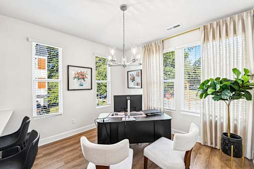 A room with a desk, chairs, and a potted plant.