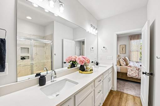 A bathroom with a white sink and a large mirror.