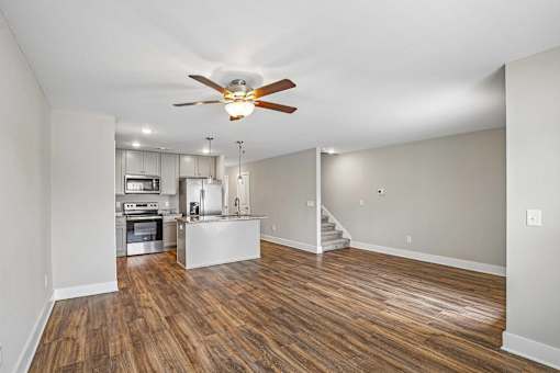 A spacious room with a ceiling fan and wooden flooring.