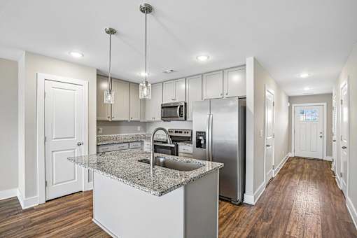 A modern kitchen with a granite countertop and stainless steel appliances.