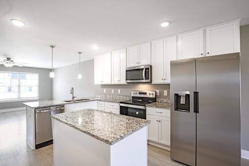 A modern kitchen with granite countertops and stainless steel appliances.