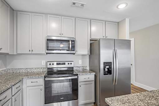 A kitchen with a stove, oven, microwave, and refrigerator.