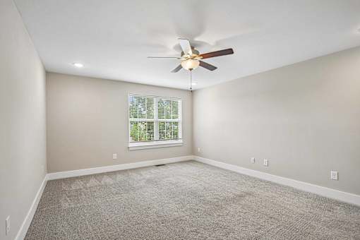 A room with a ceiling fan and a window with blinds.