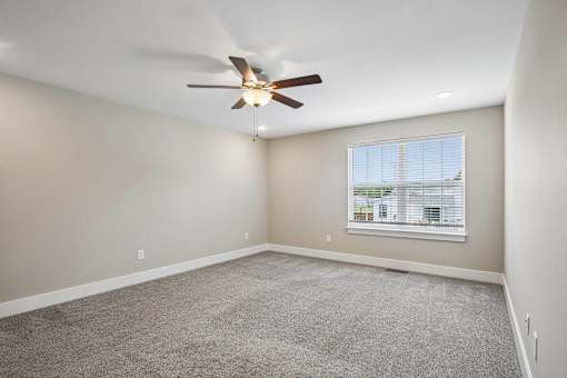 A room with a ceiling fan and a window with blinds.
