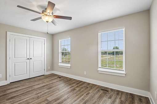 A room with a ceiling fan and a window with blinds.
