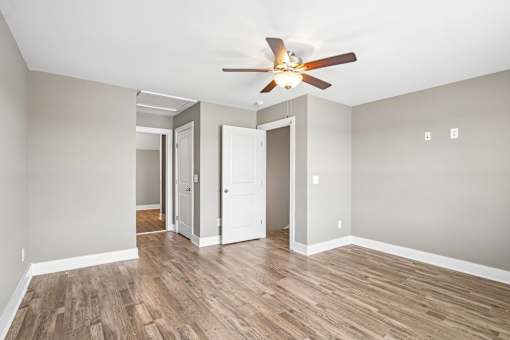 A room with a ceiling fan and wooden floors.