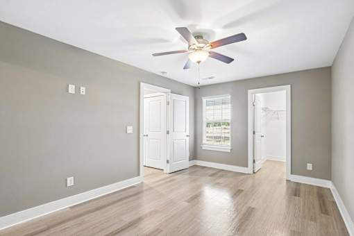 A room with a ceiling fan and wooden flooring.