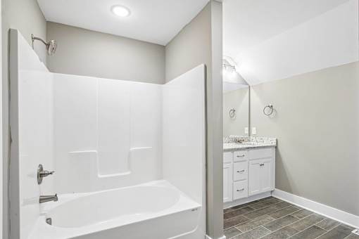 A white bathroom with a tub and a vanity.