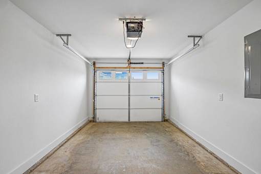 A white garage with a closed white door and a white ceiling.