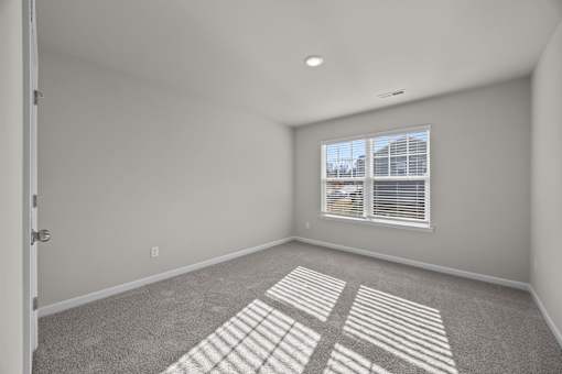 A room with a carpet floor and a window with blinds.