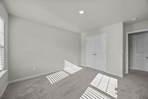 A room with a carpet and two white doors.
