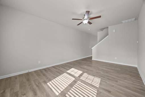 A room with a ceiling fan and wooden flooring.