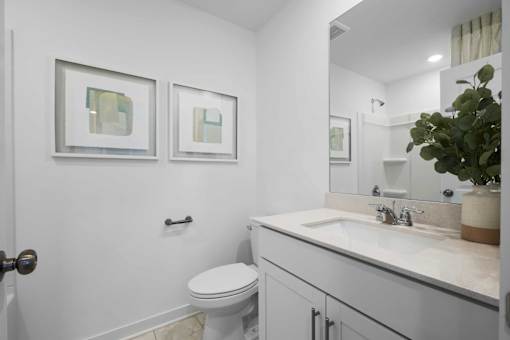 A white bathroom with a toilet, sink, and mirror.