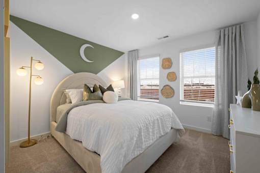 A bedroom with a large bed and a green crescent moon on the wall.