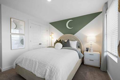 A bedroom with a white bed and a green triangular design on the wall.