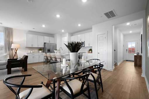 A modern dining room with a glass table and chairs.