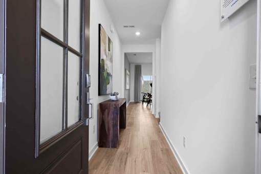 A long hallway with a brown door and a brown bench.