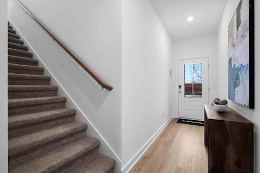 A hallway with a staircase and a door.