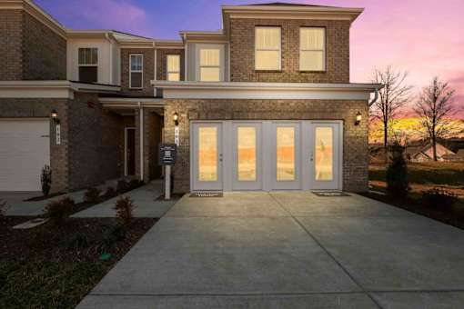 A modern house with a large front yard and a driveway.