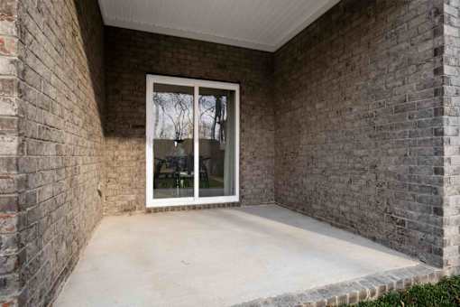 A patio with a glass door and a brick wall.