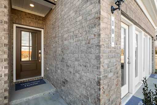 A house numbered 101 with a brown door and a blue mat on the floor.