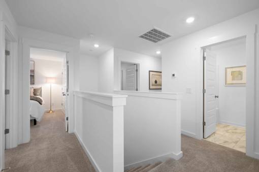 A hallway with a white wall and a carpeted floor.
